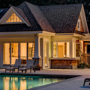 Cottage Style Pool House at Night, View of indoor climbing wall, Fully retracting bi-fold windows in the pool house kitchen allow for easy poolside food and drink service