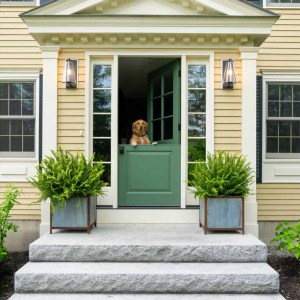 The homeowners of this 1990’s colonial wanted to update it,  both honoring the traditional style of the house, while incorporating modern touches. The original entry was misaligned with the scale of this large home. It was nonde and flat against the house creating a cramped interior.. The entry was bumped out creating more exterior dimension and improving scale. The new bump out features a traditional Greek Revival frieze with dentil molding. A dutch door allows light and air to flow into the house. The granite slab exterior stairs were reused.