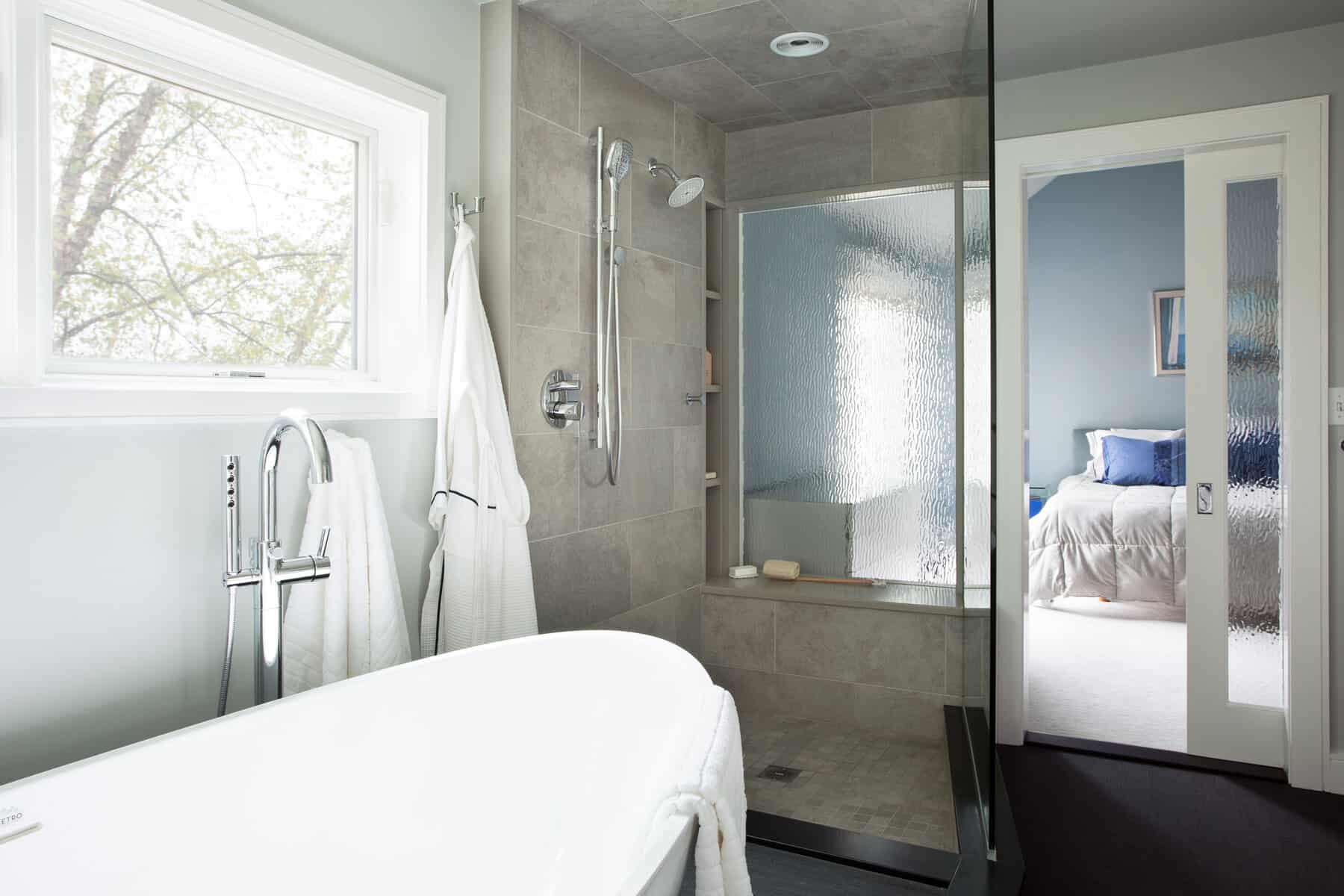 ANDOVER TOWNHOUSE MASTER BATH-The wavevue glass in the shower window and pocket door create a transparent and architecturally interesting connection between the bath and master bedroom, while still allowing for privacy. 2017 Designer Bath Shine award for best spa bath.