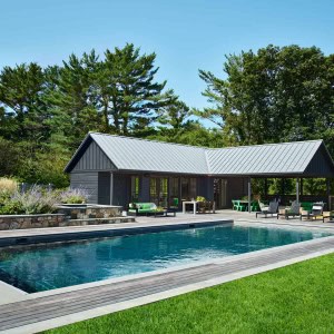 Like the farmhouse, the pool house has a metal roof and primitive wood siding. In contrast to the main house, the pool house is painted black.