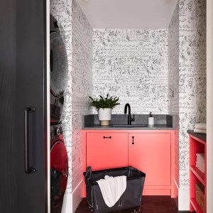 Second Floor Laundry Room-inky porcelain floor tiles are offset with salmon cabinets; rolling hamper is stashed ina slide-out copartment under the sink.