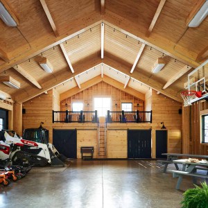 Netzero Party Barn Interior towards Kitchen with Balcony above.The barn’s conventional photovoltaic paneled roof converts sunlight into electricity, while hydronic panels heat water.