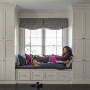 Window seat flanked by pantry cabinetry with slide out drawers for hanging files so dining room table doubles as office space