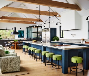 A flotilla of grass-green stools flank the 22” custom made indigo-blue island . The island is illuminated by a vast Calder-esque pendant. The light was chosen as a statement piece since the enormous kitchen presented an opportunity for a sculptural moment. A deep trough-style sink with two faucets helps to manage cleanup for large meals.