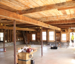 BEFORE: 1793 Barn Interior--Although the barn had a plywood ceiling from a previous renovation, a "hint" of timber-frame was exposed. The surprise discovered behind the ceiling was an expansive timber frame - oak tie beams that were 30' long, telltale hand tool marks, and other timber frame elements that indicated the barn predated 1800. (photo by Benjamin Nutter Architects)