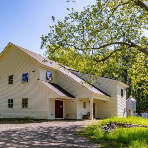 The barn side is sheathed in natural shingles and the cheesery side covered in white clapboard