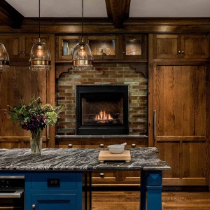 A gas fireplace and lit upper cabinets create a cozy feeling, while blue center island adds a fun splash of color.