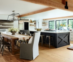 The kitchen island has a unique finish of black suede paint, playing off the metal joinery on the timbers.Decorative ceiling timbers were added, carrying the idea of the living room timber frame to this space.
