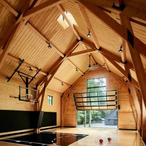 29-Fieldhouse-Barn-Interior 2.A structural Douglas Fir timber frame supports a volume of space large enough to shoot a basketball from any angle. It uses smaller dimensioned timber sizes in a carefully thought-out design that makes efficient use of the timber to structurally support such a large space.