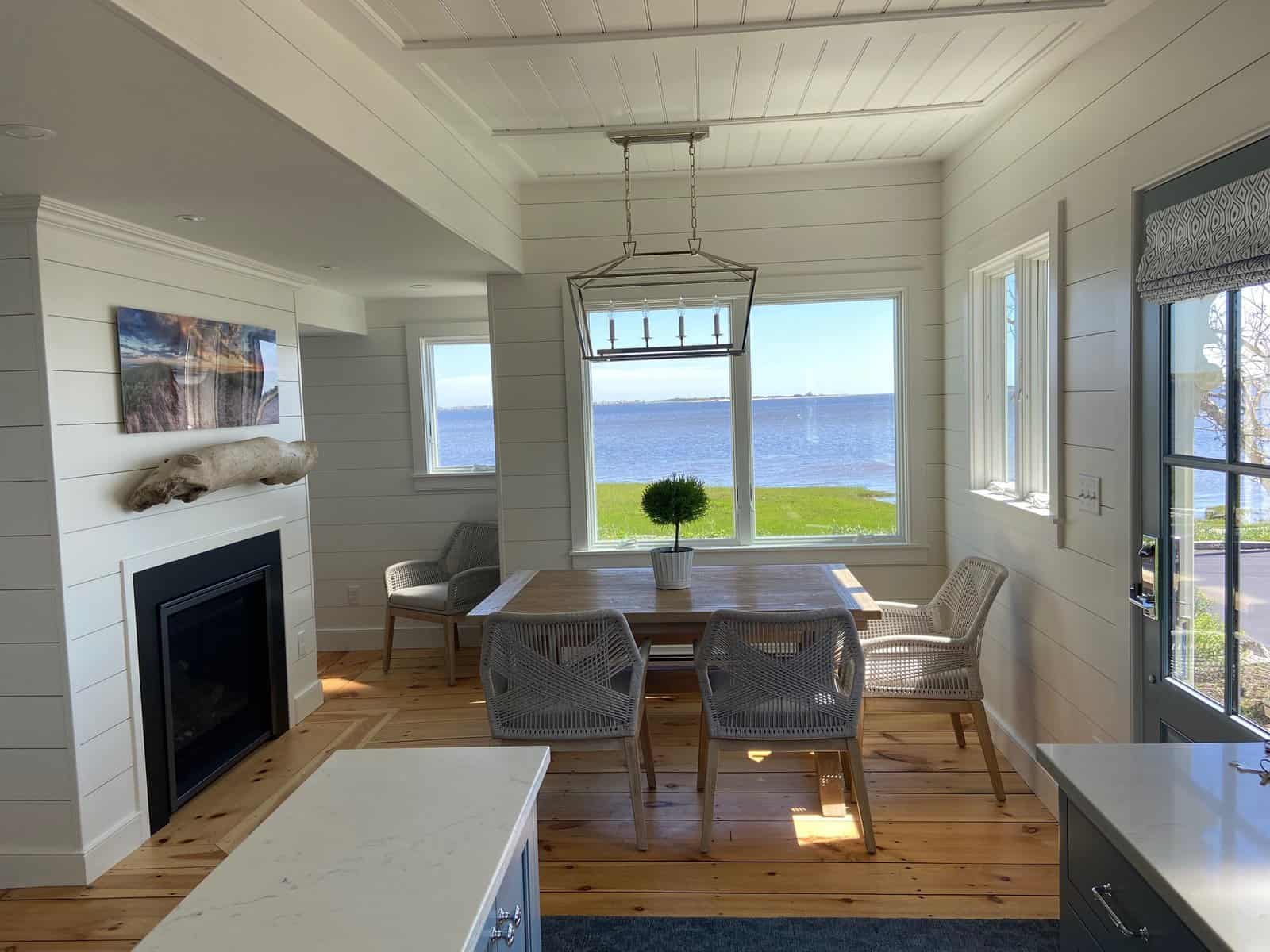 View from Kitchen to Dining Area-A visual connection between the first-floor spaces was created by removing walls and using detailed moldings, shiplap wall paneling, and beadboard ceiling paneling throughout.