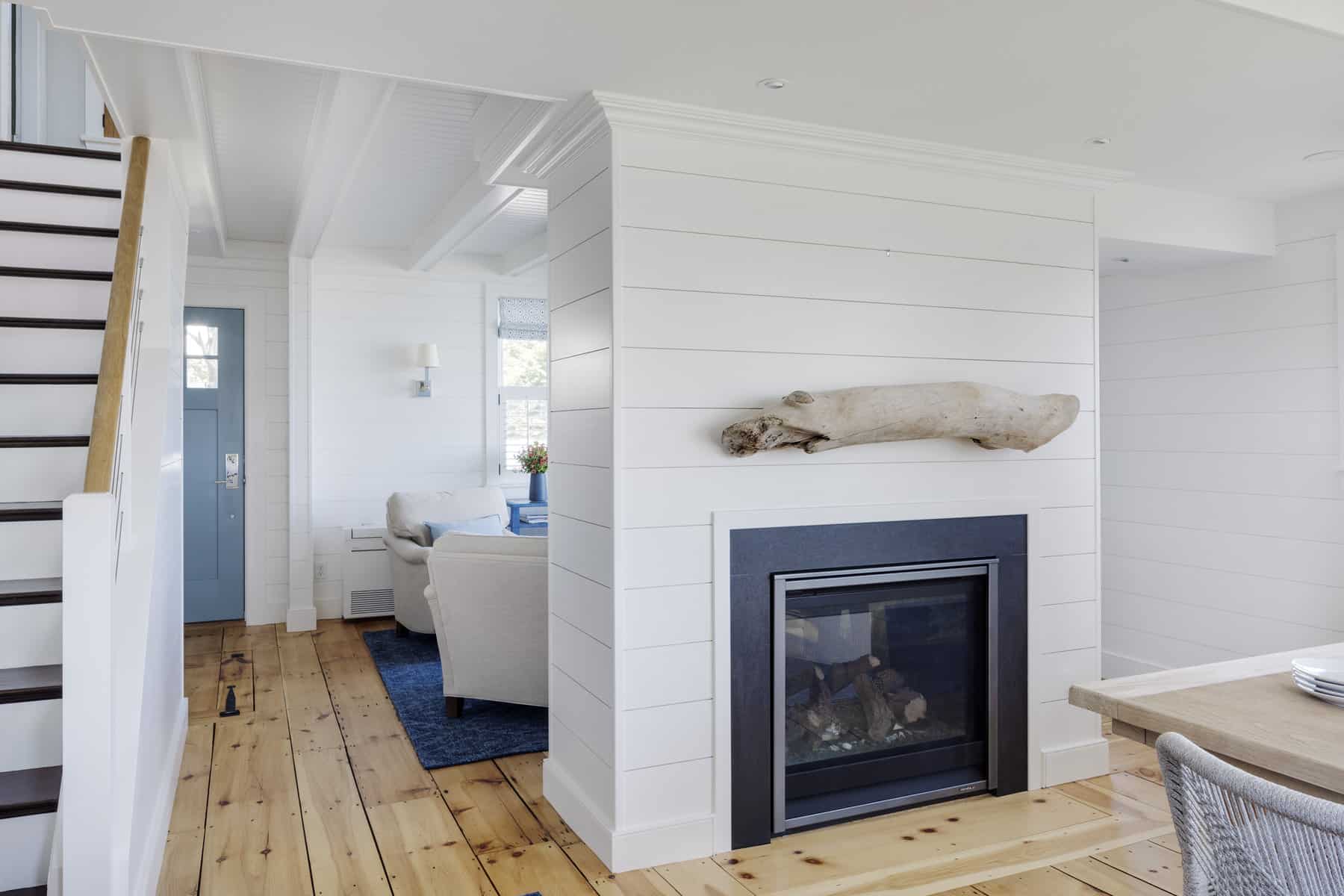 A double-sided fireplace replaced a solid wall between the living room and dining room.  The Dining Room mantle is a piece of driftwood the homeowner found on a morning beach walk on Plum Island.