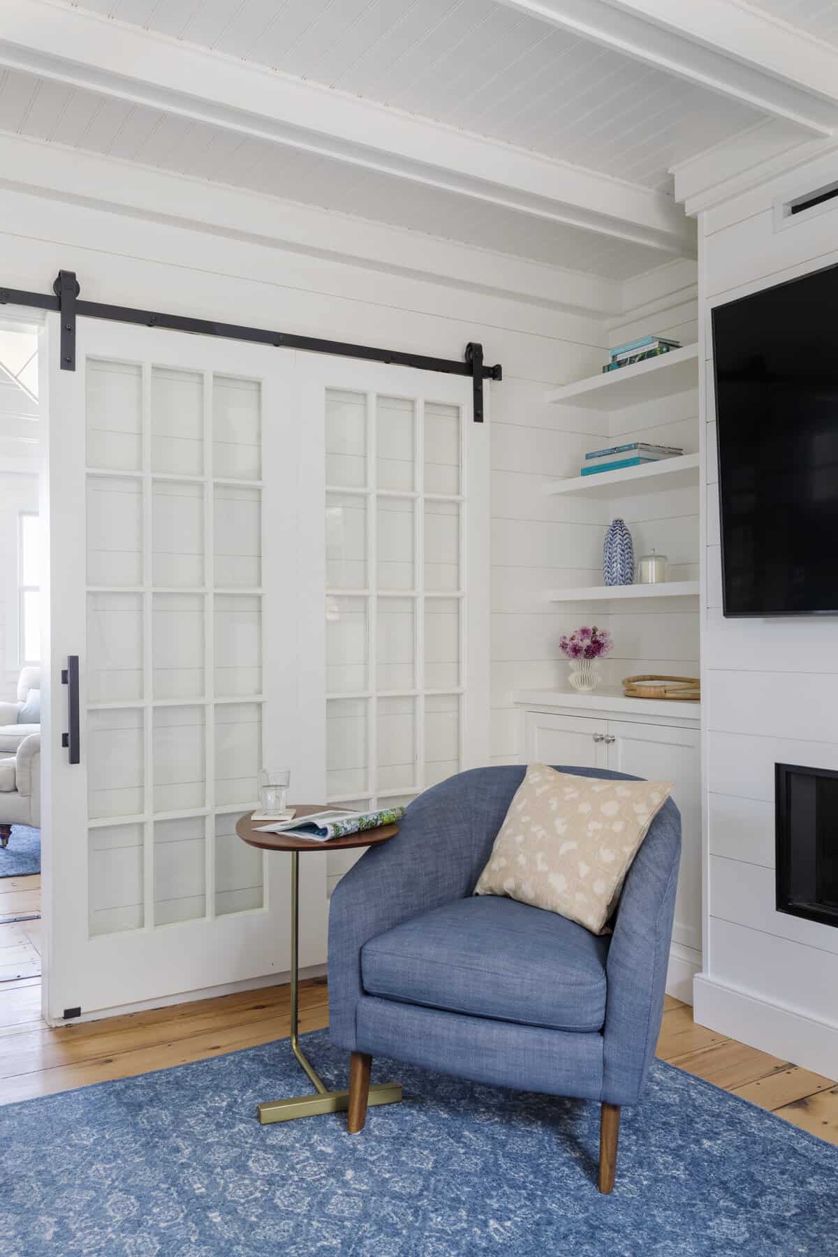 Closeup of sliding barn doors. Shiplap and beadboard paneling continue into the TV room, creating a connection to the rest of the first floor.