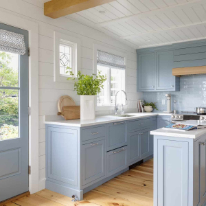 Renovated Kitchen - The inside of the house felt like the interior of a ship – small and efficient, with handcrafted millwork details.The goal was to create a minimalist, clean, serene interior that allowed the occupants to absorb the breathtaking exterior views. The kitchen island is narrow, to fit the small space, but highly functional, with a double-sided cabinet underneath, and enough space for guests to congregate around it while meals are being prepared.