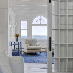 A TV room is connected to the living room. The original French doors that separated the two spaces were converted to sliding barn doors, offering better views through the living room to the water beyond.