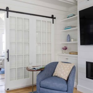 Closeup of sliding barn doors. Shiplap and beadboard paneling continue into the TV room, creating a connection to the rest of the first floor.