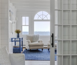 A TV room is connected to the living room. The original French doors that separated the two spaces were converted to sliding barn doors, offering better views through the living room to the water beyond.