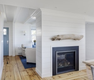 A double-sided fireplace replaced a solid wall between the living room and dining room.  The Dining Room mantle is a piece of driftwood the homeowner found on a morning beach walk on Plum Island.
