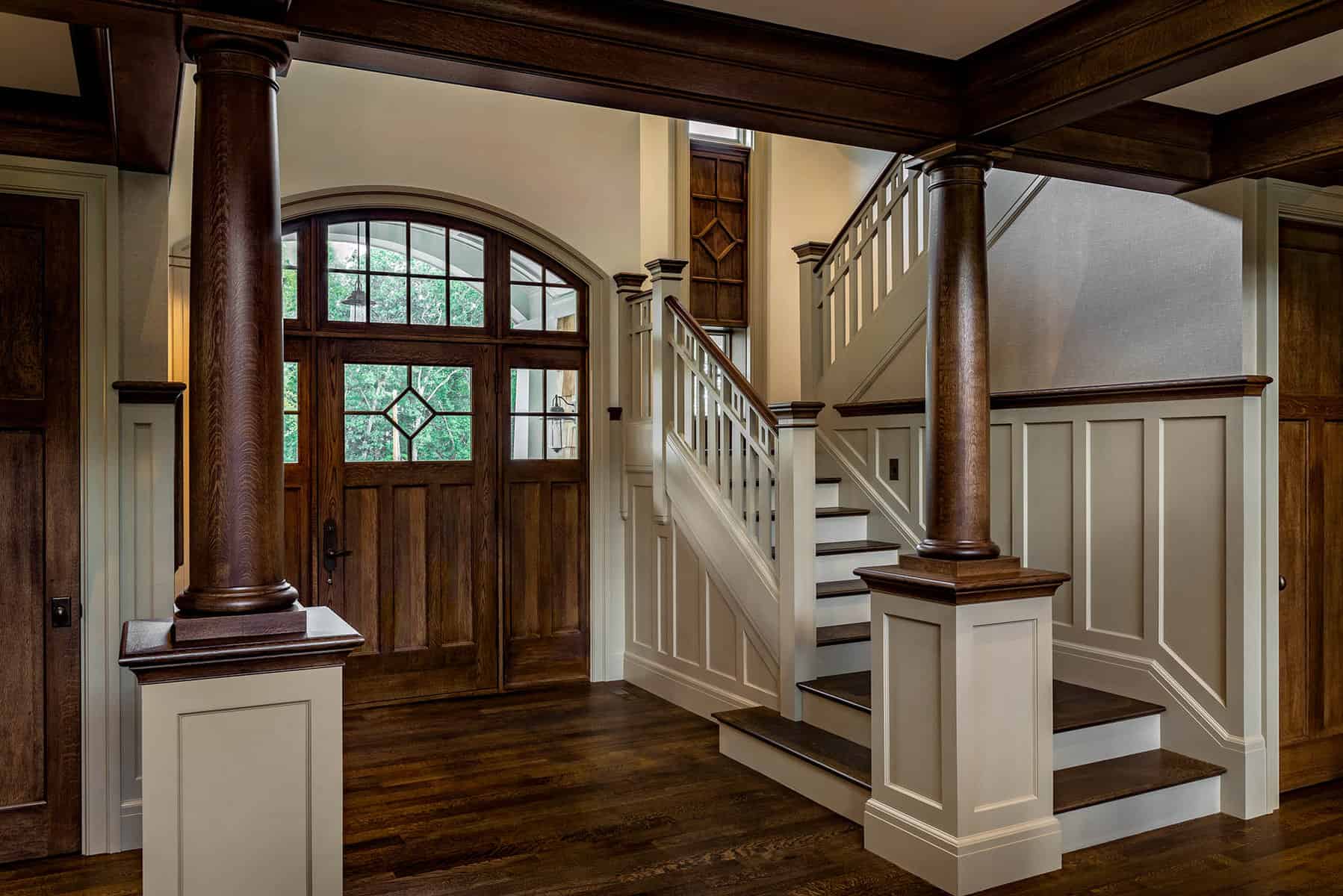 Front Entry Interior-- white oak columns and coffered ceilings. Tall panel on stair window echoes door style
