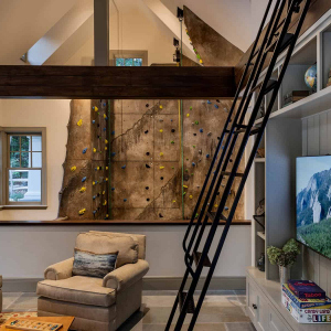 Poolhouse interior. A living space overlooks a 3 story climbing wall. Ladder leads to a sleeping loft overlooking the living space