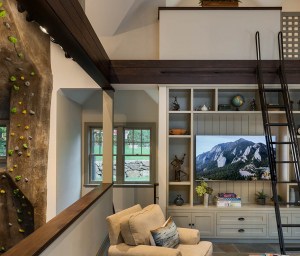 The living space overlooks the climbing wall, and a sleeping loft above overlooks the living space.