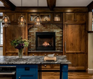 A gas fireplace and lit upper cabinets create a cozy feeling, while blue center island adds a fun splash of color.