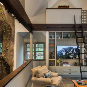 Poolhouse living room overlooks full scale climbing wall while a ladder leads to sleeping loft.