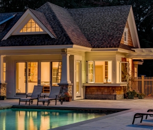 Cottage Style Pool House at Night, View of indoor climbing wall, Fully retracting bi-fold windows in the pool house kitchen allow for easy poolside food and drink service