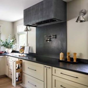 The custom cooktop hood features an aged acid washed zinc finish with a modern profile.