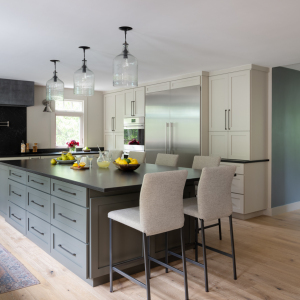 The centerpiece is a kitchen island with seating for 6 and a quartz composite countertop that has the appearance of soapstone, without the maintenance. The taupe and deep green cabinets and island are historic colors, inspired by researching old New England homes. 